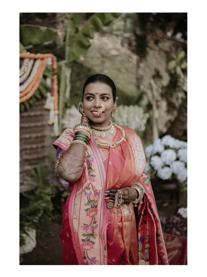 A beautiful three-quarter portrait of the bride, showcasing her traditional jewelry and the elegant drape of her nauwari saree.