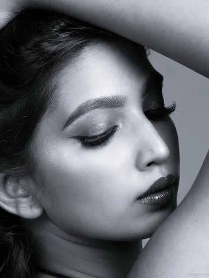 A dramatic black and white close-up, with the model's eyes closed.