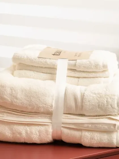 A set of off-white towels in the same modern bathroom setup. We ensure the color accuracy of products is maintained in the final images.