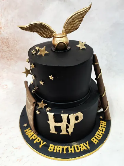 We capture the magic of the wizarding world with this two-tiered Harry Potter themed cake. The design features the iconic golden snitch, a wizard's wand, and the HP logo in gold against a stark black fondant, creating a sophisticated and spellbinding tribute for a fan's special day.