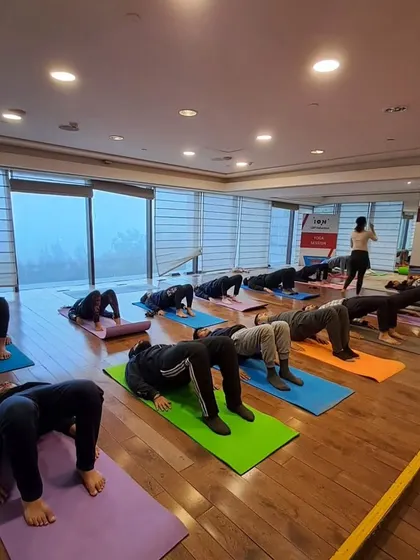 A corporate class working on Setu Bandhasana, or Bridge Pose, to open the chest and strengthen the back.