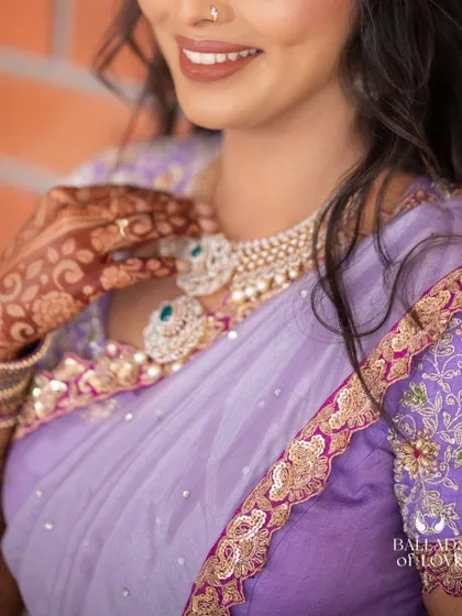 A close-up shot showing the detail on the blouse sleeve and the bride's henna-adorned hands.