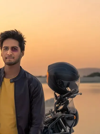 A golden hour portrait by the water. The warm, soft light of the sunset creates a beautiful, cinematic mood for this casual men's lifestyle shot.