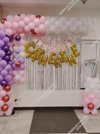 A pastel balloon frame with a silver fringe backdrop for a 7th birthday party.