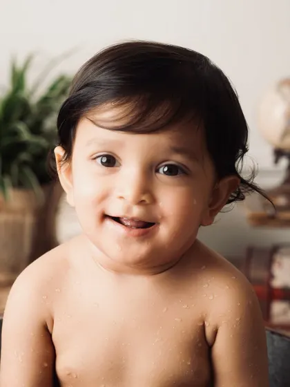 A sweet, close-up portrait after the splash, with droplets of water on his face and a gentle smile.