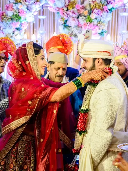 A wider view of the varmala exchange. You can see the family members and the beautiful floral decor, giving a full picture of this happy wedding ceremony.