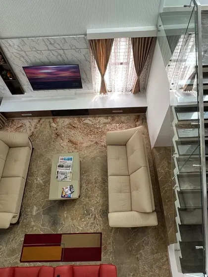 A top-down view of a living area in the 'Hongirana' project, showing the arrangement of furniture on a richly patterned marble floor next to a modern staircase.