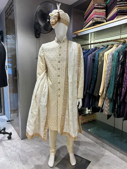 A classic groom's look never goes out of style. This is a beautifully crafted off-white sherwani with subtle self-embroidery, paired with a matching pagri (turban) and stole. It’s a testament to timeless elegance for the main wedding ceremony.