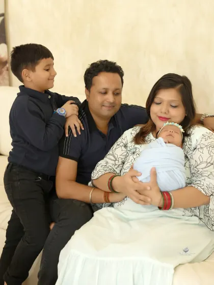 A candid moment of interaction within the family. The older brother looks on as his mother holds the new baby, capturing a real and sweet memory.