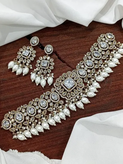 A versatile choker set available in multiple colors including white pearl, ruby, emerald, and pastel pink. The design features a central square motif with hanging beads, making it a popular choice for various festive occasions.
