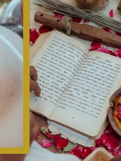 A close-up of the priest's hands on a traditional scripture during the ceremony, surrounded by flower petals.