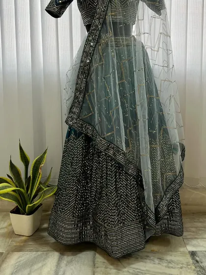 The full view of the teal blue lehenga, showing the coordinated embroidery on the skirt and blouse, paired with a lightweight, embellished net dupatta.