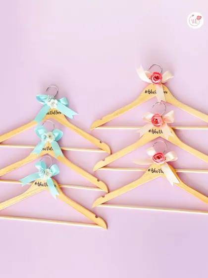 A side-by-side look at the two custom hanger designs, one with a blue bow and one with a pink bow, perfect for the bride and groom.