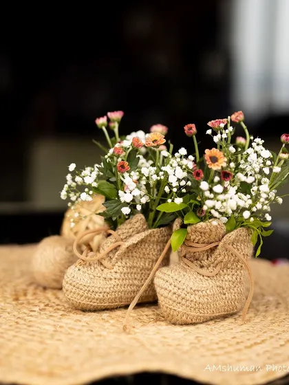 A close-up of a party favor from a boho baby shower. The small jute-wrapped baby shoes filled with flowers are a unique and adorable keepsake for guests.