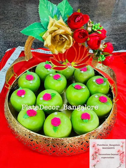 Green apples decorated with small pink roses, arranged in a golden basket. This design is perfect for engagements or puberty ceremonies.