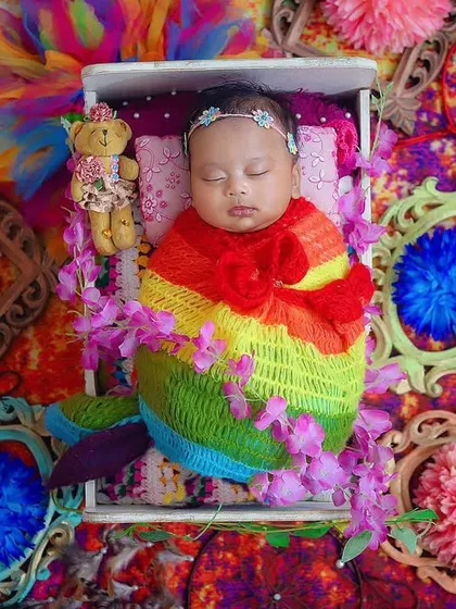 A sleeping beauty surrounded by the colors of Holi. This newborn is peacefully dreaming in a bed of vibrant textures and props, a beautiful way to celebrate her first festival.