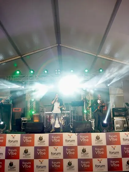 The band on a fully lit stage at Forum Vibe. We bring a complete audio-visual experience to every performance.