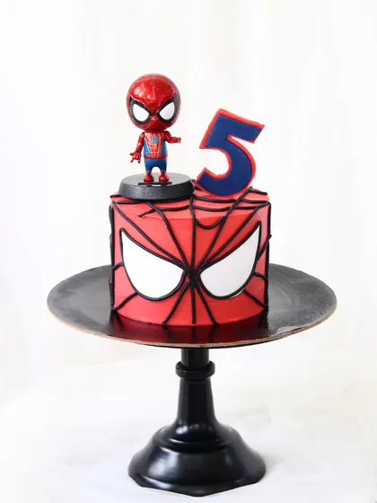 A simple yet powerful Spider-Man cake for a fifth birthday. This design features the iconic Spidey mask on a square cake, topped with a fun bobblehead figure.