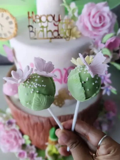 A whimsical Tinkerbell-themed birthday cake. This custom creation includes matching cake pops, showing how we can create a full dessert spread for a themed party.