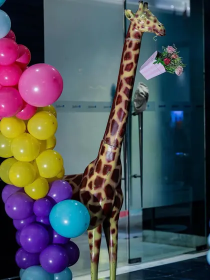 A life-sized giraffe prop decorated with a bouquet of flowers, standing next to a vibrant balloon arch. It's these quirky details that make my events unique and memorable.
