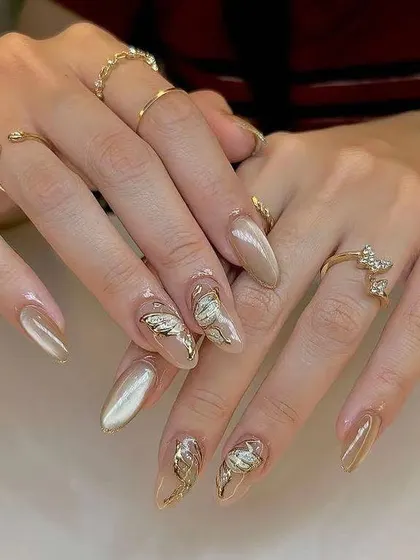 A sophisticated and trendy look. These almond-shaped extensions have a pearlescent, cat-eye base with delicate, 3D gold butterfly and metallic accents for a touch of elegance.