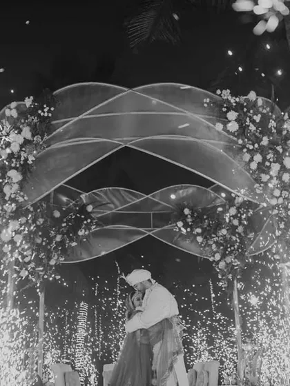 The same magical moment in black and white, emphasizing the emotion and the sparkling fireworks against the night sky. The decor provides a timeless frame for the couple's love story.