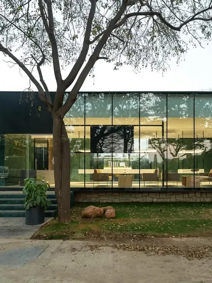 The VPG Experience Center at dusk. The transparent facade glows from within, acting as a lantern and a beacon on the busy Whitefield Main Road.