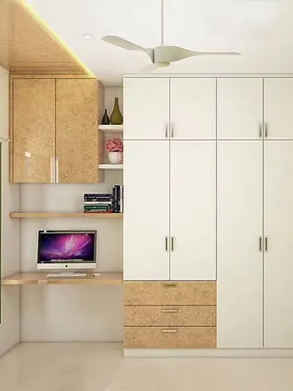 A compact and efficient bedroom design featuring a wardrobe with an integrated study desk. The light wood and white finish keeps the room feeling bright and spacious.