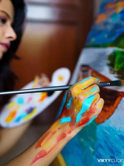 A close-up shot focusing on my paint-splattered hand as I work on a canvas. The vibrant colors on my skin are a temporary reflection of the artwork I'm creating.