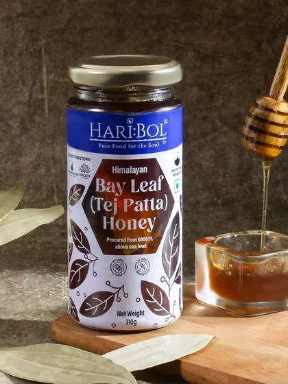 A dark and moody shot for Himalayan Bay Leaf Honey. The dripping honey and bay leaf props create a rich, aromatic visual that highlights the unique flavor of the product.