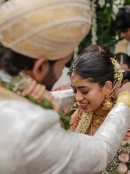 A tender moment during the Varmaala ceremony. The groom placing the garland on the bride is a key ritual, captured here with a focus on their gentle interaction.