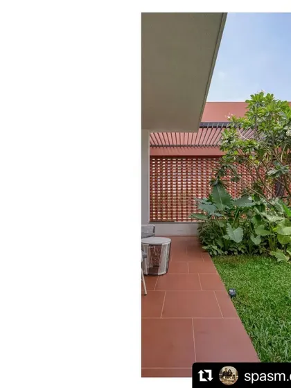 A quiet patio at the Ishtika house, where the interior opens onto a private lawn. The space is screened by a brick jali wall and lush planting, creating a perfect spot for morning coffee.