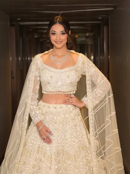 An angelic look in all white. The soft glam makeup with subtle shimmer and a chic messy ponytail creates a modern and sophisticated style, perfect for a sangeet or engagement party.