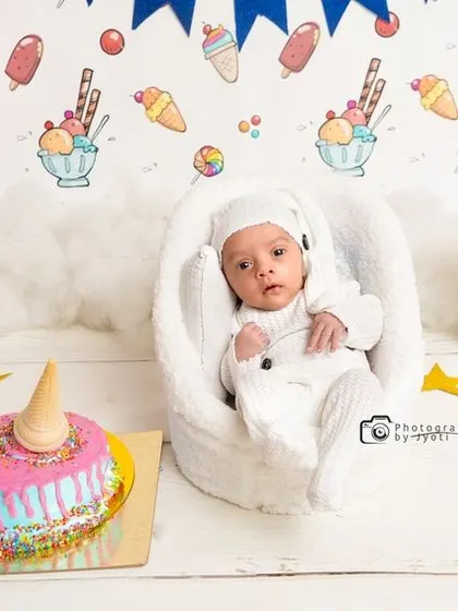 A wider view of the sweet treats-themed newborn session, showing the full setup with pink balloons, gift boxes, and a festive banner.
