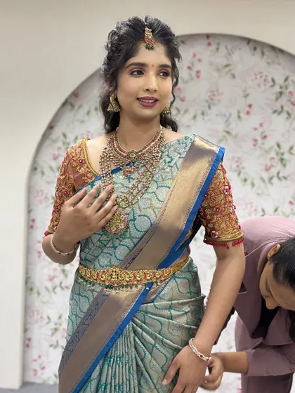 A candid moment during a draping session. We take care of every little detail to ensure the saree is pinned securely and looks neat from all sides.