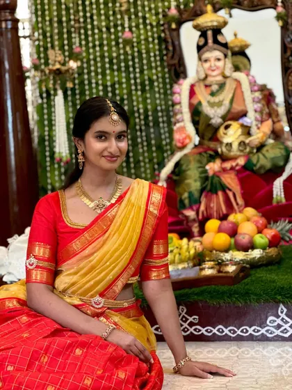 Our client celebrating a traditional ceremony. Her custom red blouse for the half saree ensemble was designed to be both comfortable and elegant for the occasion.
