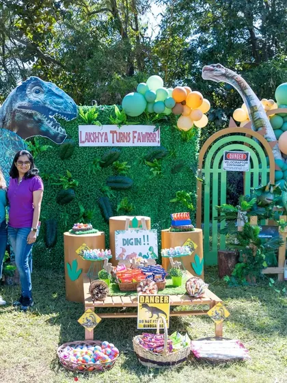 A photo of me with the happy clients in front of the dinosaur party backdrop I designed and created.