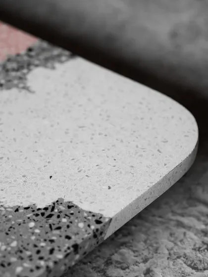 The beautifully curved edge of a custom multicolor terrazzo tabletop. This detail shot highlights the smooth finish and the seamless blend of different colored sections.