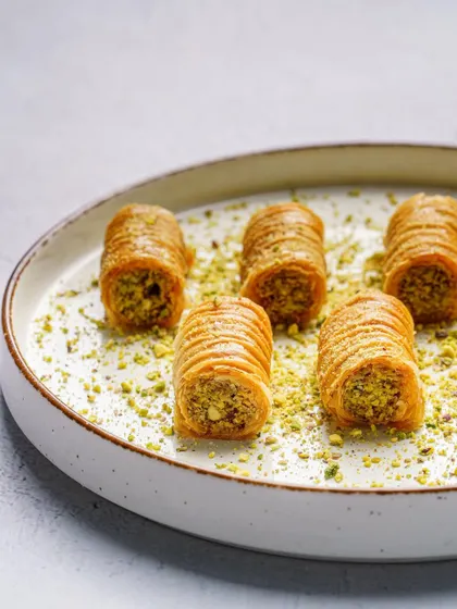 A clean, minimalist shot of baklava rolls. This elegant and simple composition puts the focus entirely on the delicate details of the dessert, perfect for a gourmet brand.