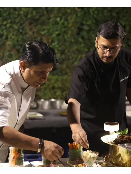 A moment of mentorship, as a senior chef guides a junior chef in plating, showcasing our culture of teamwork and excellence.