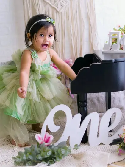 A moment of pure joy and excitement. This little girl in her green dress can't contain her happiness during her first birthday photoshoot.