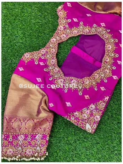 A modern take on a traditional blouse. This magenta piece features a large circular back cutout, framed with delicate floral embroidery that matches the work on the contrasting gold sleeves.