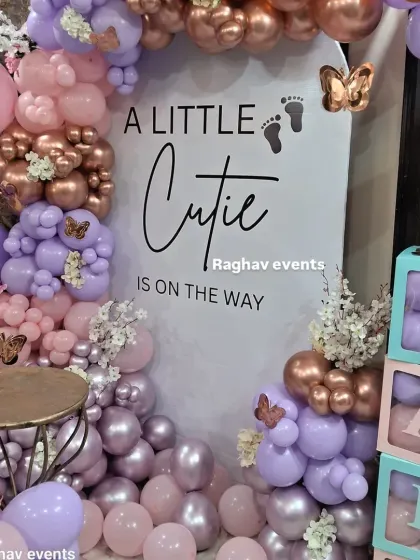 A close-up of the "A Little Cutie" baby shower setup, highlighting the balloon arrangement and the 'BABY' boxes.