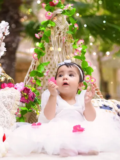 Looking up at the falling petals, this moment from an outdoor first birthday session is pure magic.