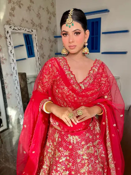 A full-length view showcasing how the makeup, hair, and outfit work together. The clean, pulled-back hair and radiant makeup ensure the bride herself is the main focus, looking every bit the part of a classic Indian bride.