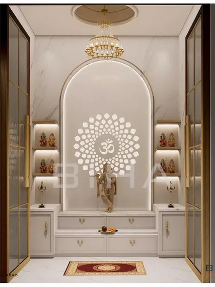 This pooja room design demonstrates our ability to create modern sacred spaces. We used white marble for its purity, framing an arched niche with soft, integrated lighting. The backlit 'Om' mandala creates a serene focal point, while glass doors with brass frames provide a sense of enclosure without sacrificing visual connection to the home.