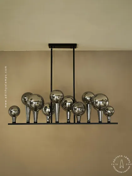 A playful yet chic linear chandelier featuring a series of chrome-finished glass bubbles. The highly reflective surface and modern design make it a striking addition to a kitchen island or a contemporary dining space.