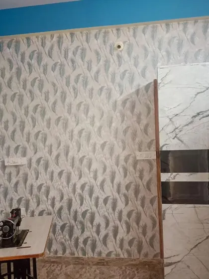 A bedroom wall with a grey feather pattern wallpaper. The design is simple and elegant, complementing the modern furniture.