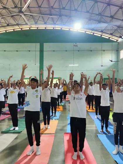 Students raising their arms in a unified asana, filling the hall with energy and mindfulness during our Goa event.