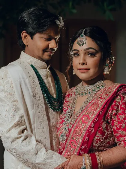 A classic portrait of the bride and groom. Her traditional red lehenga is paired with stunning diamond and emerald jewellery, and her makeup is kept timeless and elegant.